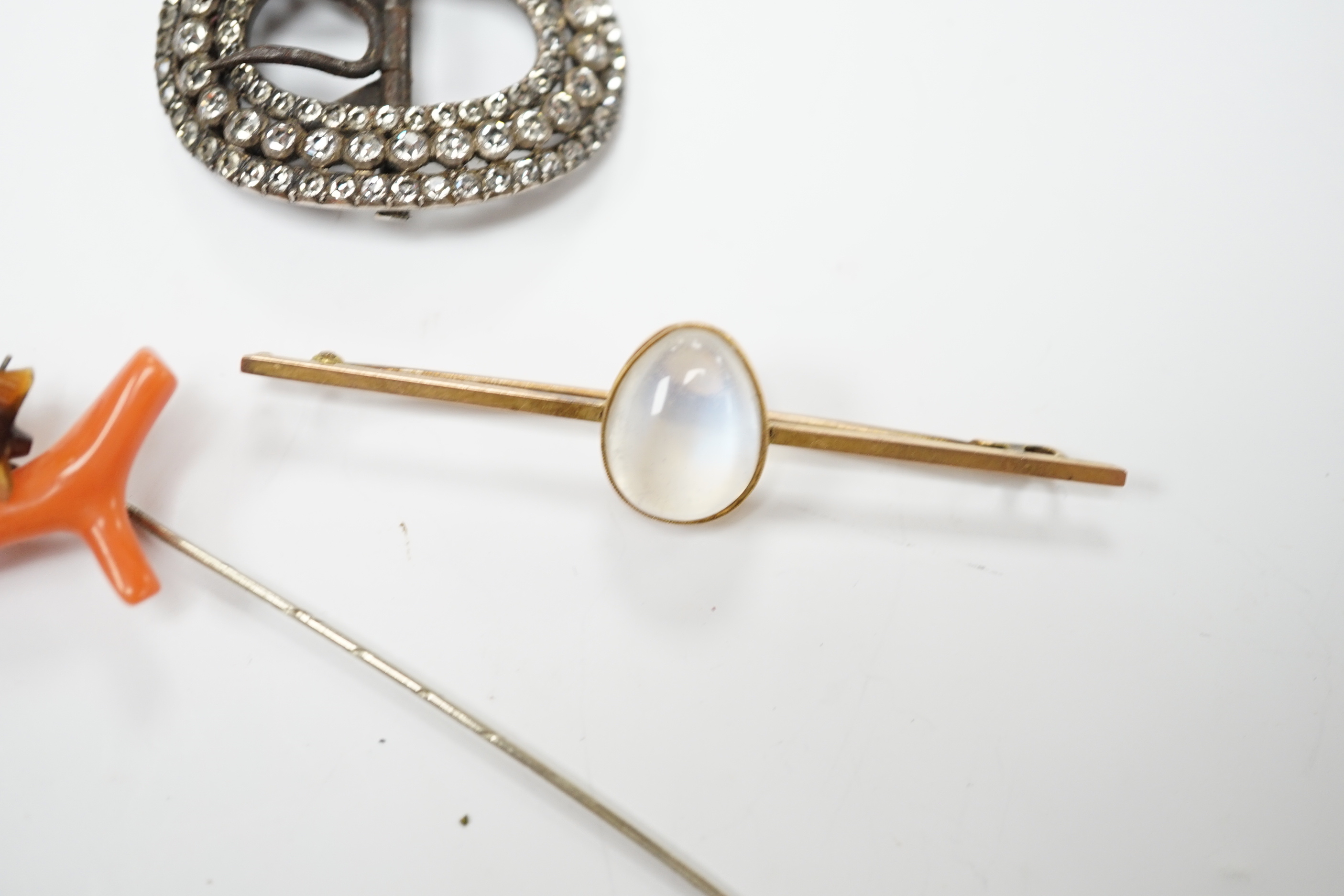 A 9ct and cabochon moonstone set bar brooch, 63mm, a coral and horn set bug stick pin and a paste set buckle.